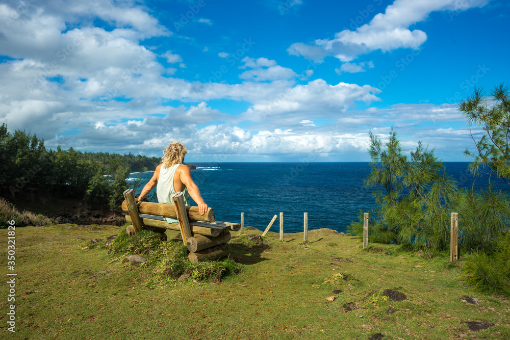A young man sits and enjoys a view of the beautiful ocean. Mauritius