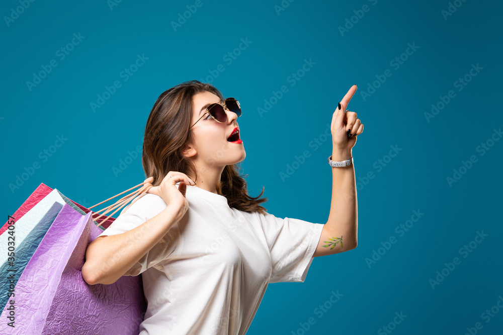 Young stylish beautiful girl in sunglasses is walking with multi-colored shopping bags. Concept shopping and store. Young stylish beautiful girl in sunglasses is walking with multi-colored shopping bags. Concept shopping and store.
