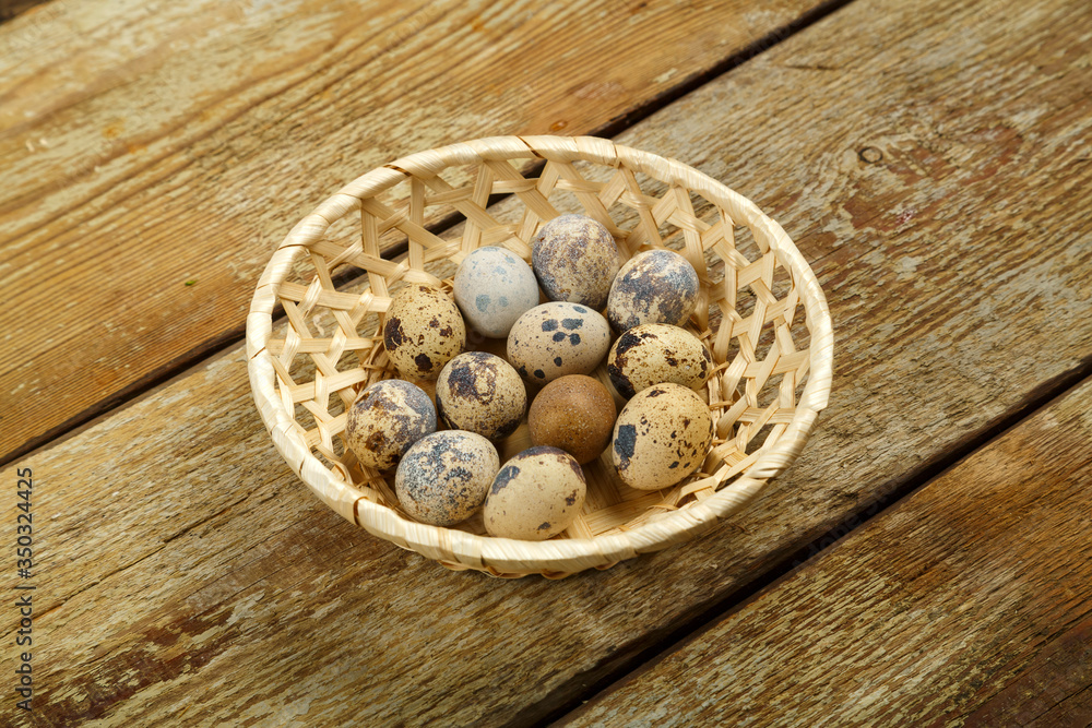 Fresh quail eggs in a wicker basket on a wooden table. Fresh quail eggs in a wicker basket on a wooden table.
