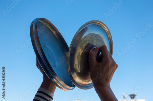 Canvas-taulu Woman hands banging pot lids against blue sky
