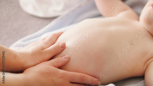 Mother massaging baby tummy. Baby skin care and development concept. photo