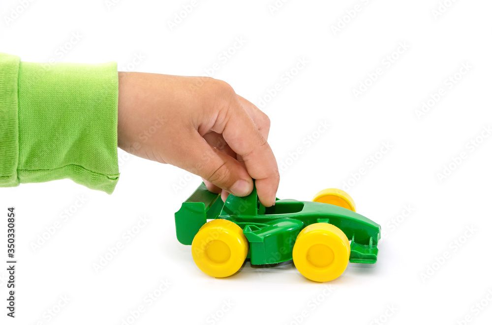 green toy car in a child's hand isolated on a white background. Hand is playing with a toy car on white. green toy car in a child's hand isolated on a white background. Hand is playing with a toy car on white.