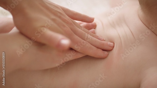 Female masseuse doing medical back massage to infant. Health care concept. Close up.