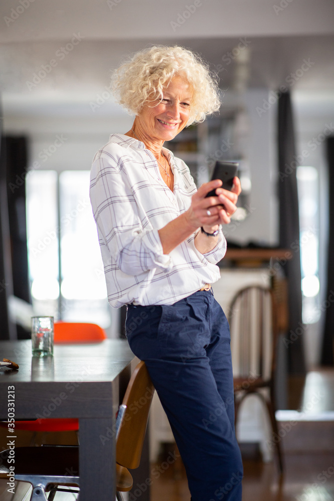 older woman standing at home with mobile phone