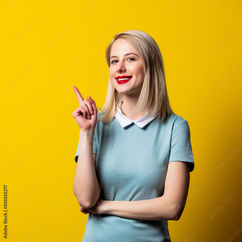 Smiling blonde girl in blue dress on yellow background Smiling blonde girl in blue dress on yellow background