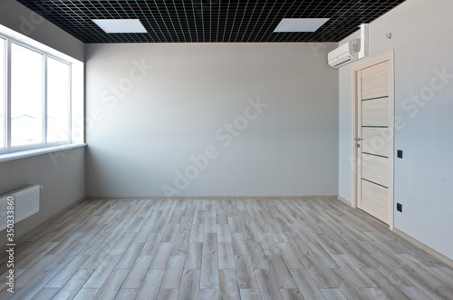 An empty office room. The large window. Gray walls. Laminate floor