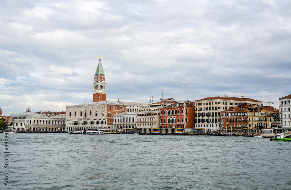 Picturesque view of Bell tower of Saint Mark and the Ducal Palace from the sea in summer. Waterfront landmark buildings and many boats on the venetian lagoon. Venice, Italy