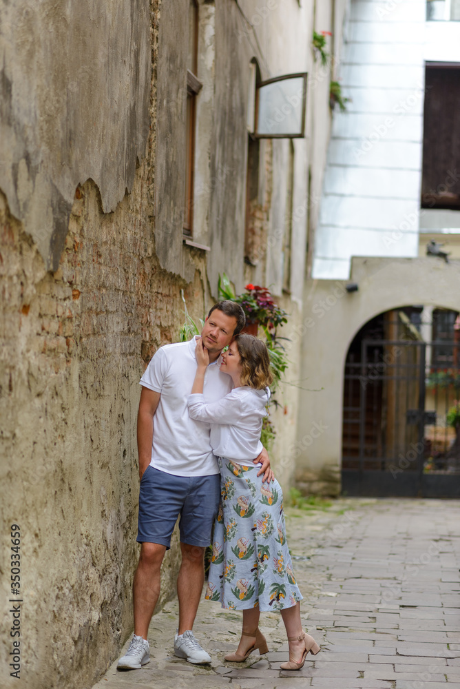 Two lovers hug on the streets of the old city during a date. A couple is standing near an old brick wall.
