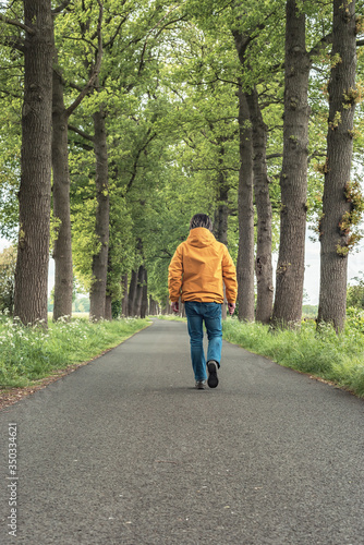 Wallpaper Mural Man in yellow jacket and jeans walks on country road in springtime. Torontodigital.ca