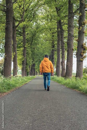 Wallpaper Mural Man in yellow jacket and jeans walks on country road in springtime. Torontodigital.ca