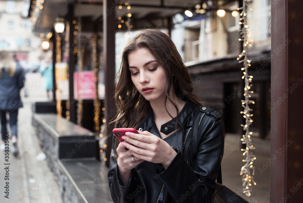 pretty european woman is using smartphone sitting on city background pretty european woman is using smartphone sitting on city background