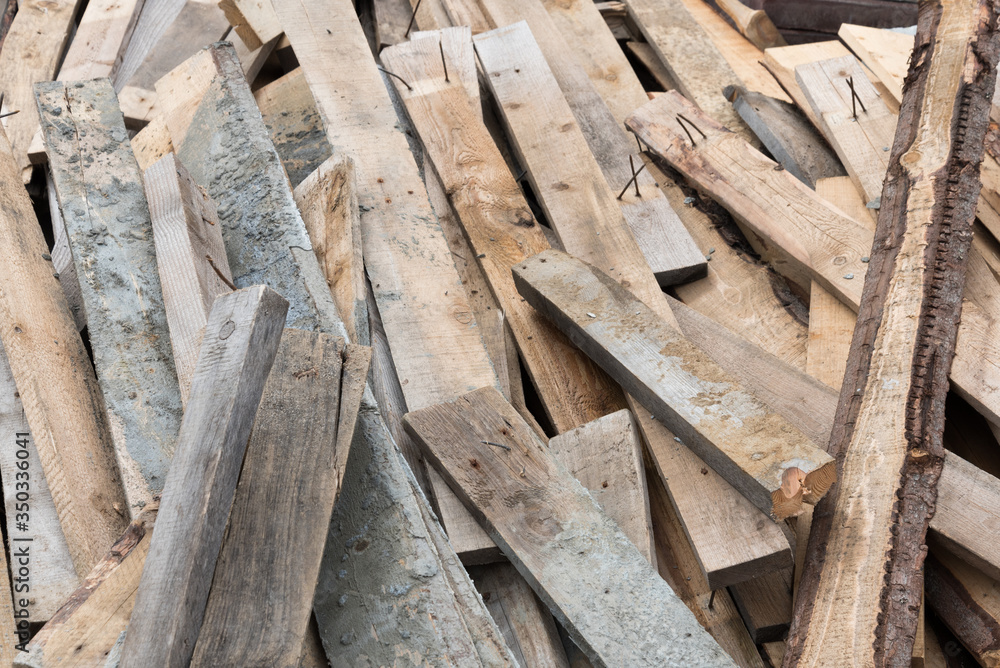 A pile of wooden planks in close-up. Nails protrude from the boards. Background, texture, and construction. A pile of wooden planks in close-up. Nails protrude from the boards. Background, texture, and construction.