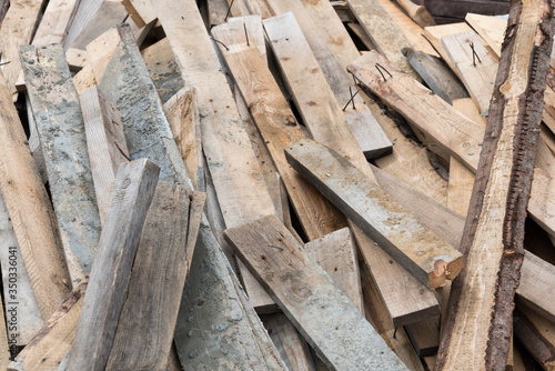 A pile of wooden planks in close-up. Nails protrude from the boards. Background, texture, and construction.