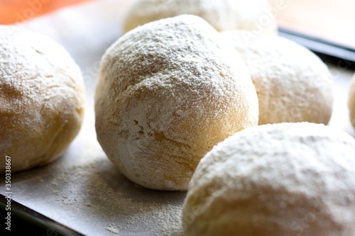 White pambazos placed on a metal tray, around it a scale. Diffuse background photo