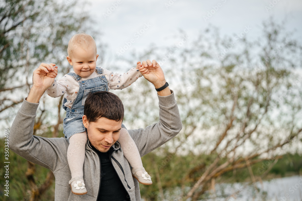 young father and his little daughter on the neck walk together on the street. Relationship family child and father. young father and his little daughter on the neck walk together on the street. Relationship family child and father.