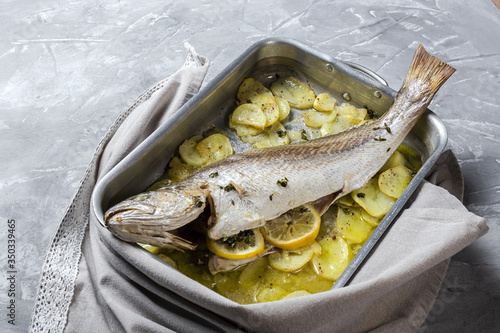 Fresh raw sea bass fish prepared for roasting with potatoes photo