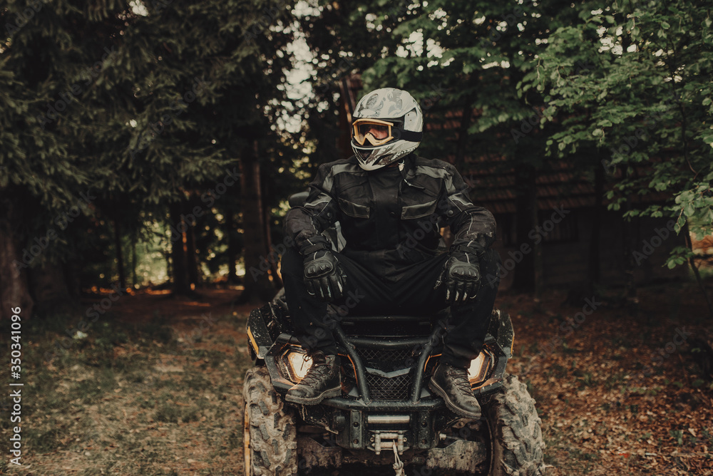 Man sitting on quad in forest and preparing for ride Man sitting on quad in forest and preparing for ride