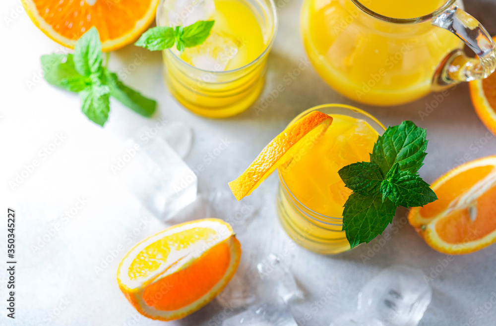 Fresh orange juice, orange slices, mint leaves and ice on a wooden table. Fresh orange juice, orange slices, mint leaves and ice on a wooden table.