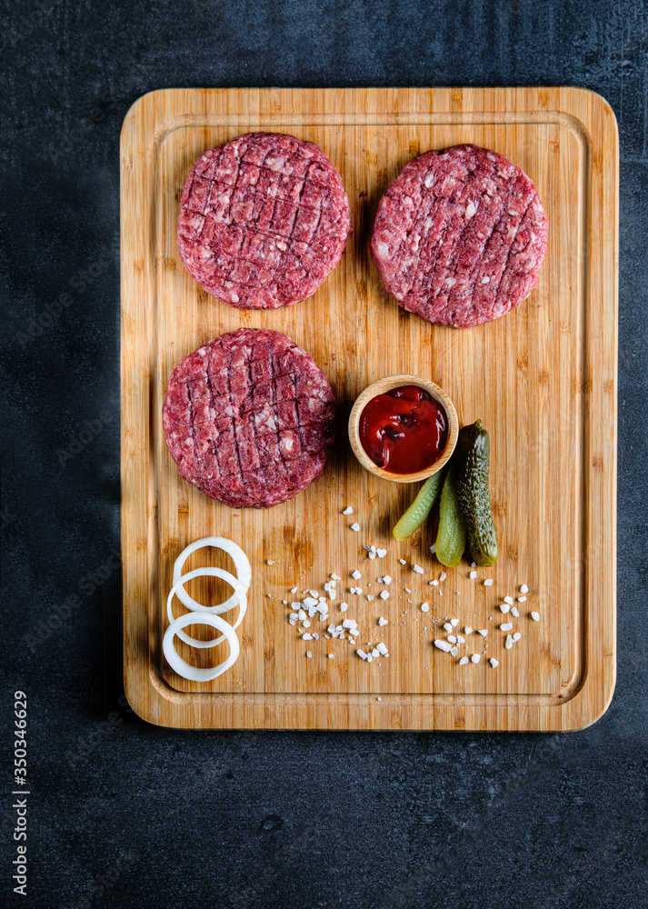 Red burger meat closeup on black background. Top view. Food preparation. Red burger meat closeup on black background. Top view. Food preparation.