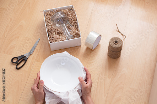 Woman packs plates in paper when moving to another house