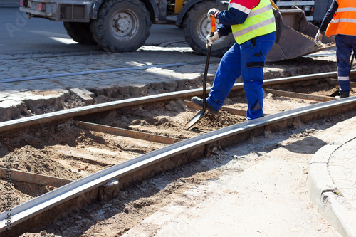 Worker with shovel digs at replacement tram rail