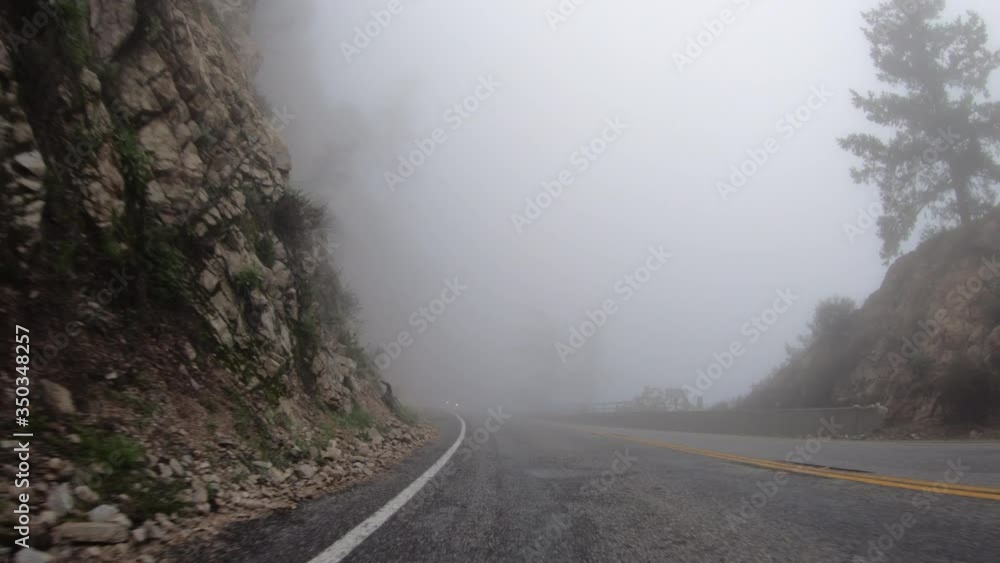 Driving rear view through fog and clouds on Angeles Crest Highway in the San Gabriel Mountains near Los Angeles in Southern California. Driving rear view through fog and clouds on Angeles Crest Highway in the San Gabriel Mountains near Los Angeles in Southern California.