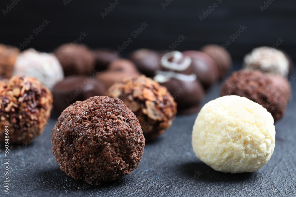 Different tasty chocolate candies on black table, closeup