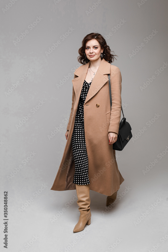 Young caucasian female with short chestnut wavy hair in long brown coat goes to home Young caucasian female with short chestnut wavy hair in long brown coat goes to home