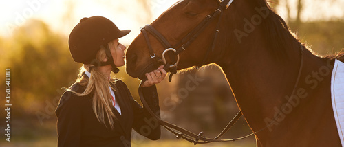 Beautiful horse rider girl stands near a horse on a farm 