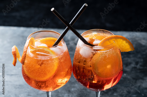 Fotografering Two glasses of classic italian aperitif aperol spritz cocktail with slice of ora