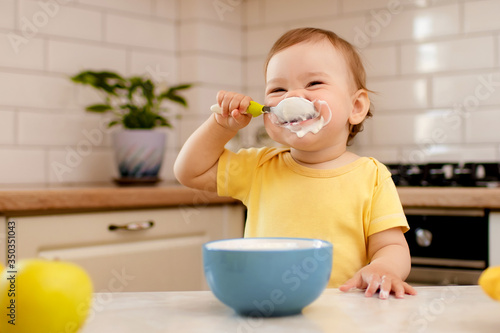 Happy child girl in the kitchen eats a delicious cottage cheese and porridge.
