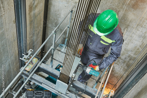 lift machinist repairing elevator in lift shaft photo