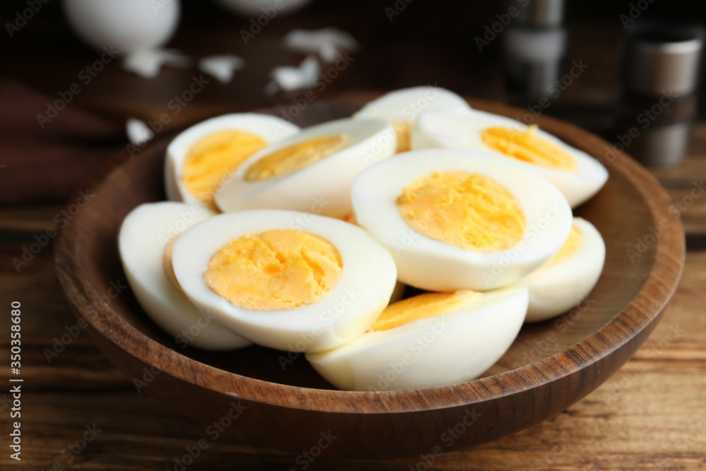 Cut hard boiled chicken eggs in wooden bowl on table Cut hard boiled chicken eggs in wooden bowl on table