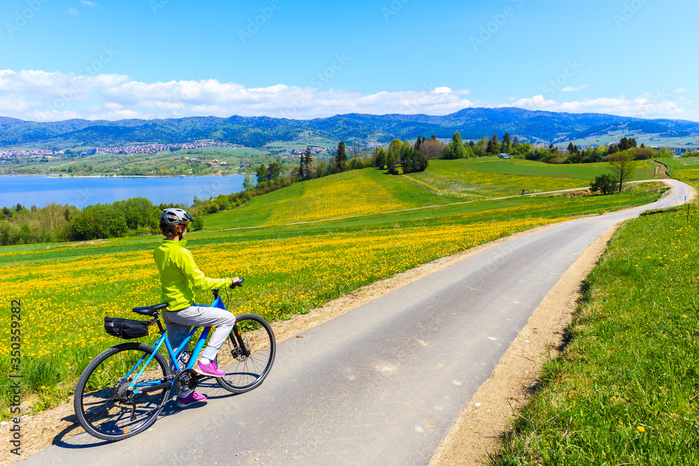 Woman cycling around Czorsztynskie lake near Falsztyn village on sunny spring day, Pieniny Mountains, Poland Woman cycling around Czorsztynskie lake near Falsztyn village on sunny spring day, Pieniny Mountains, Poland