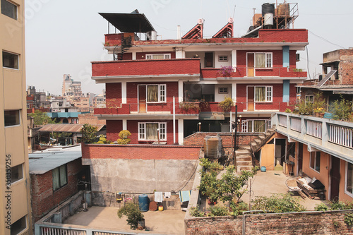 View of common residential building made from red bricks in Kathmandu city, Nepal. Solar panels and water tanks on rooftop. Residential district theme.