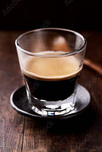 Coffee in glass cup on rustic wooden background. Close up.	