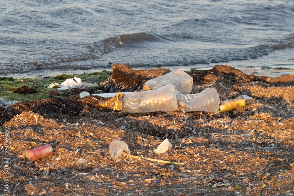 Plastic bottles left on the dirty sand beach with various garbages Plastic bottles left on the dirty sand beach with various garbages