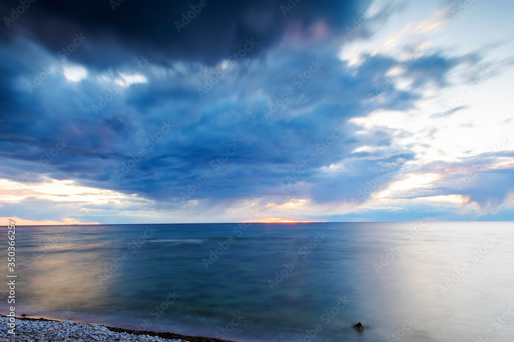 Rain clouds over ocean during sunset, long exposure Rain clouds over ocean during sunset, long exposure