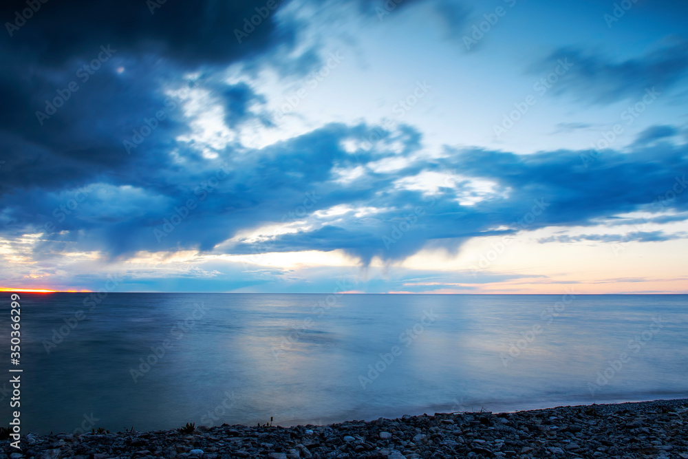Obraz premium Rain clouds over ocean during sunset, long exposure
