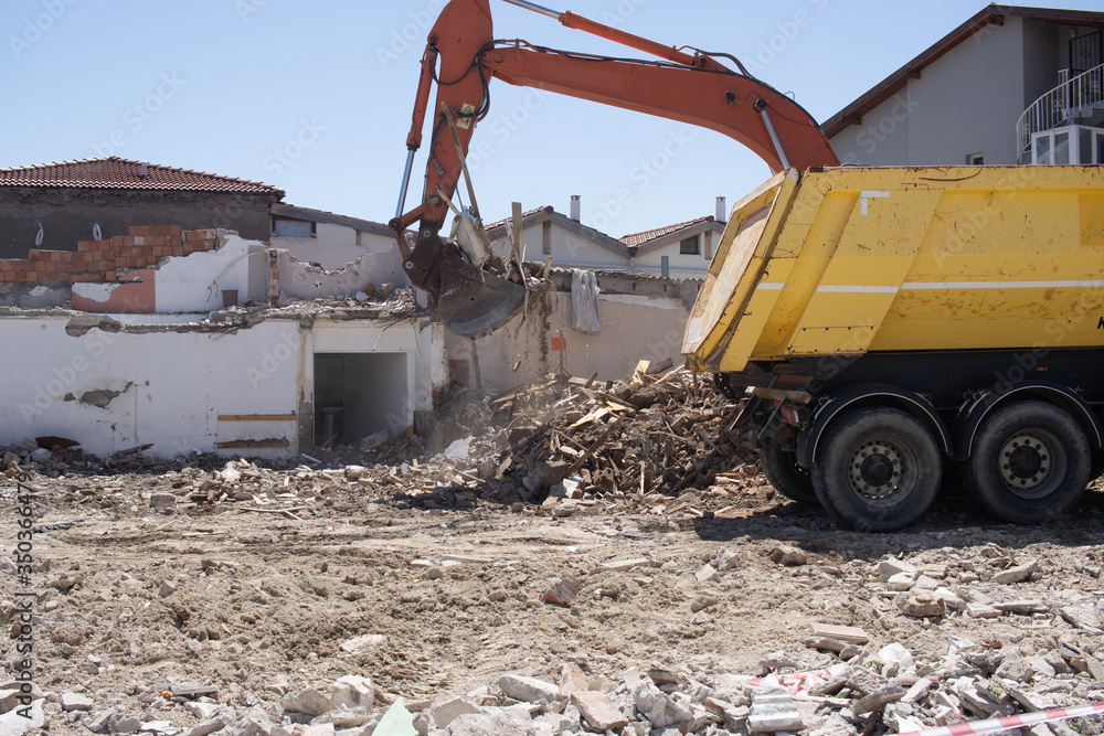 Fototapeta premium excavator loading debris of a destroyed building in truck.