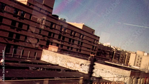 Retro looking archival footage filmed on New York City subway looking out through subway window at tracks and passing train with apartments and graffiti in the distance photo