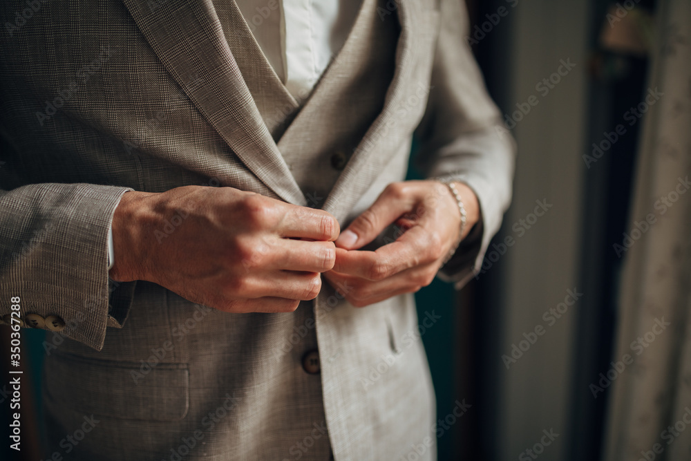 Close-up of a man in a tux fixing his cufflink. groom bow tie cufflinks