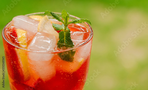 Fresh cold lemonade with strawberries and lemon on wooden background. Citric, healthy