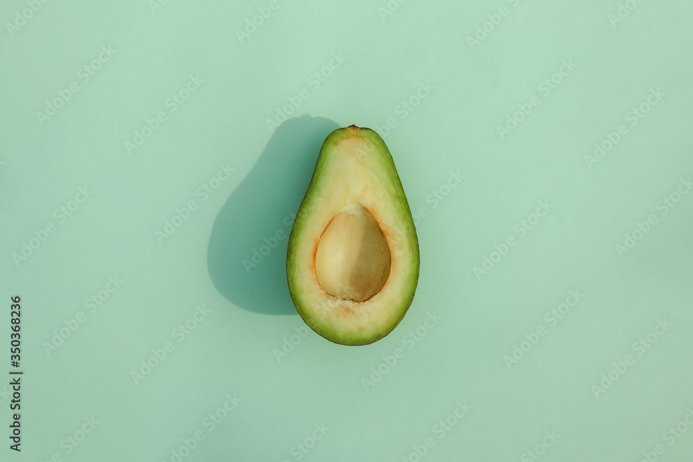 avocado cut on a colored background top view with a hard shadow