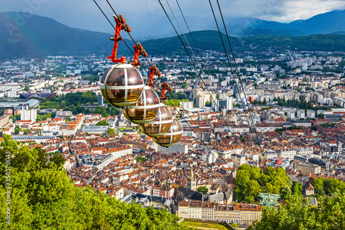 Picturesque aerial view of Grenoble city, Auvergne-Rhone-Alpes region, France. Grenoble-Bastille cable car on the foreground. French Alps on the background