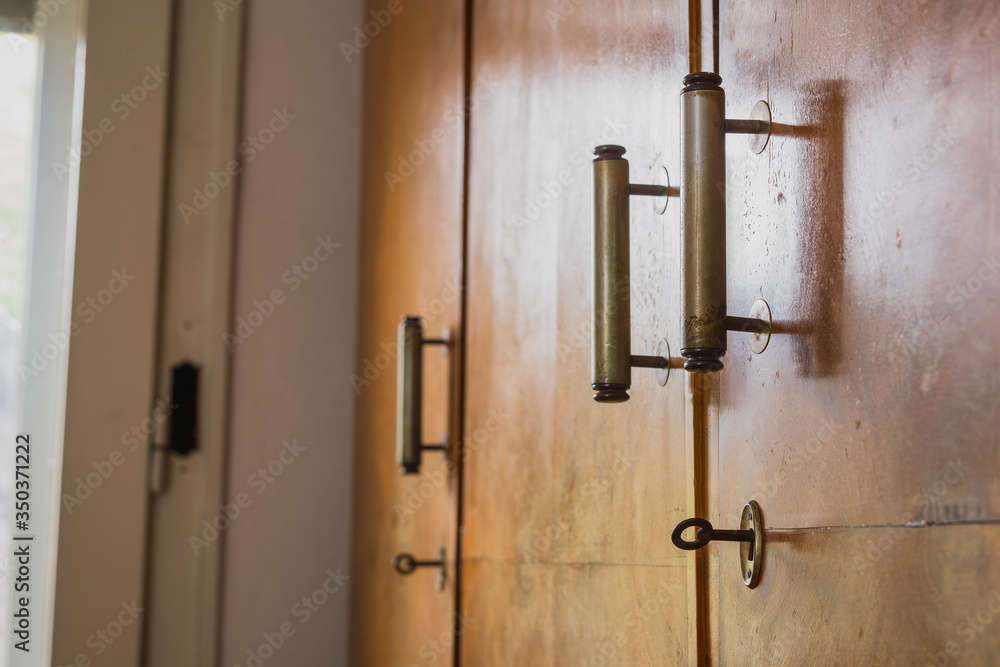 Old knob, lock and handles on an old wooden furniture. Visible also lock and a key on an old decayed wooden door Old knob, lock and handles on an old wooden furniture. Visible also lock and a key on an old decayed wooden door