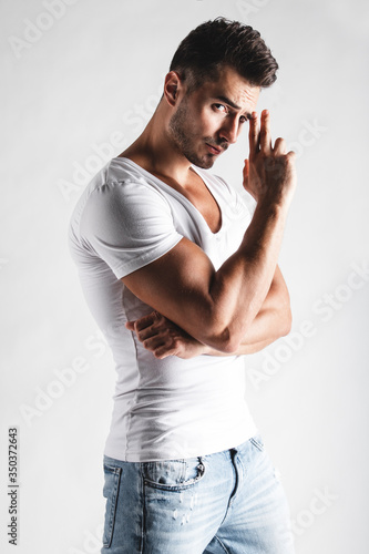Male beauty concept. Portrait of handsome young man with stylish haircut posing over white background. Perfect hair & skin. Close up. Studio shot
