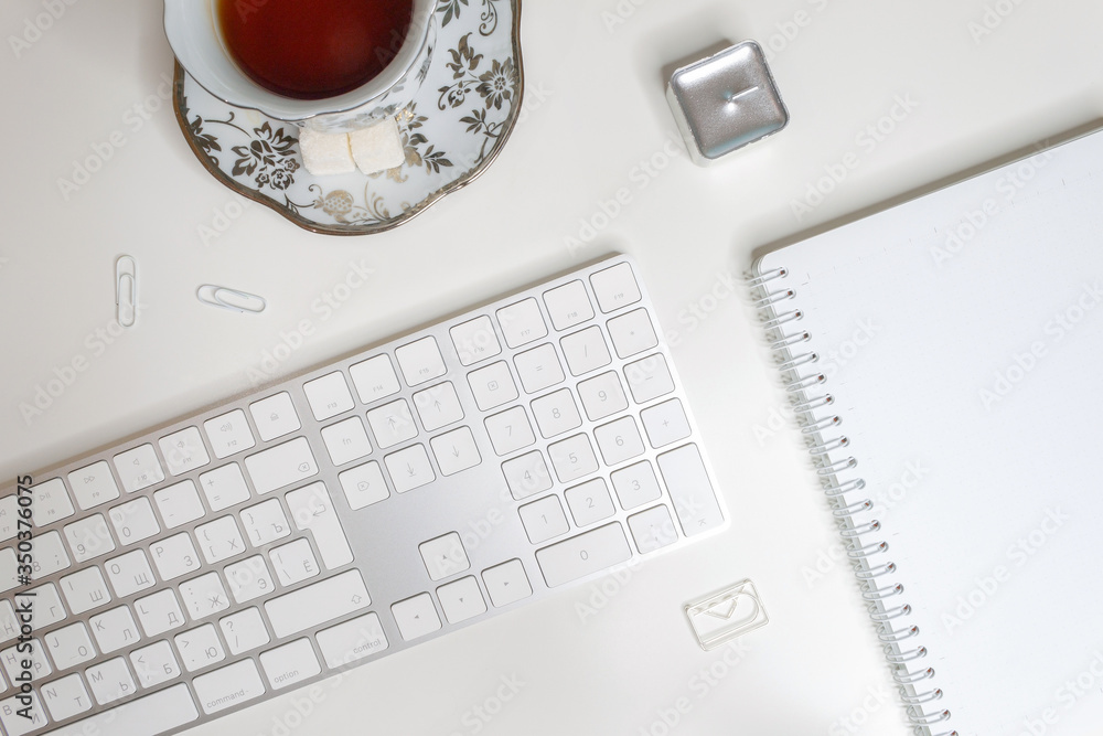 Flat lay of workplace with blank notepad, tea cup and keyboard on white background Flat lay of workplace with blank notepad, tea cup and keyboard on white background