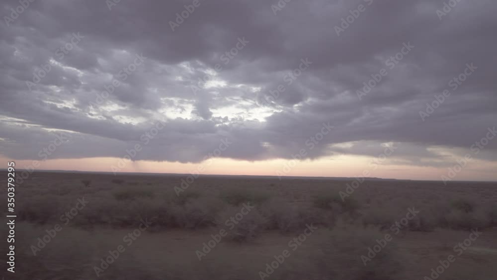 Panning shot of cloudy sky over landscape during sunset seen through moving train window - Swakopmund, Namibia Panning shot of cloudy sky over landscape during sunset seen through moving train window - Swakopmund, Namibia