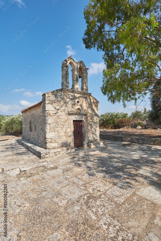 Rural village chapel on Crete island with belfry, bell tower. Travel destination, local landmark. Countryside on the Eastern part of the Mediterranean island.